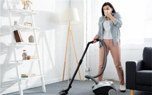 Frau beim Staubsaugen mit Taschentuch in der Hand